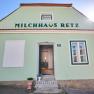 Grünes Gebäude mit der Aufschrift 'Milchhaus Retz' und einer offenen Tür.