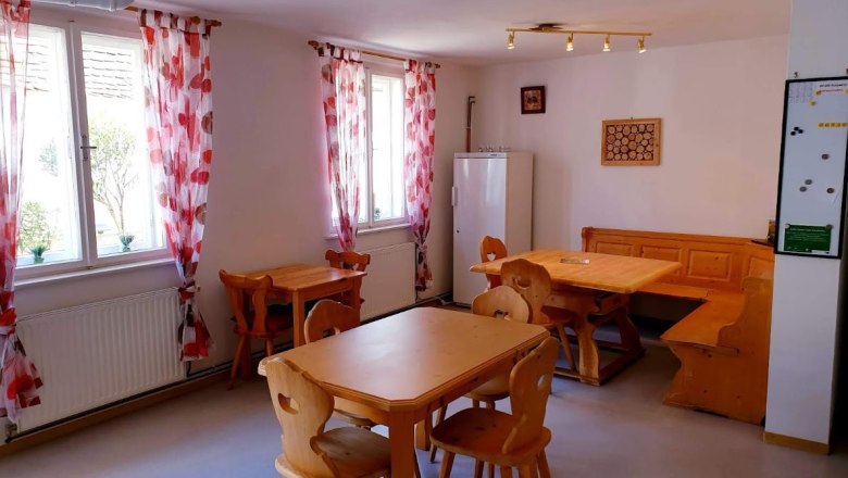 Gemütlicher Raum mit Holzmöbeln und roten Vorhängen.